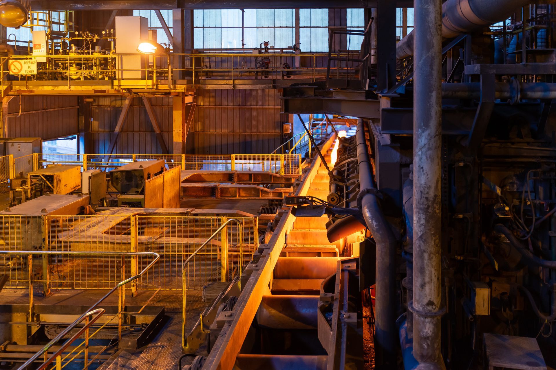 Industrial factory interior with glowing orange machinery and metal catwalks