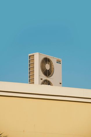 Building rooftop with a large beige air-conditioning unit against a clear blue sky