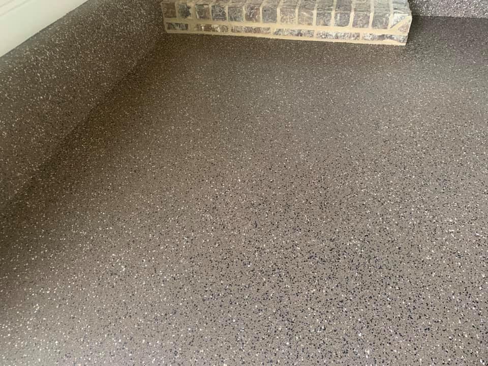 A close up of a gray floor with a brick wall in the background.