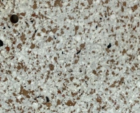 A close up of a brown and white tile with a hole in the middle.