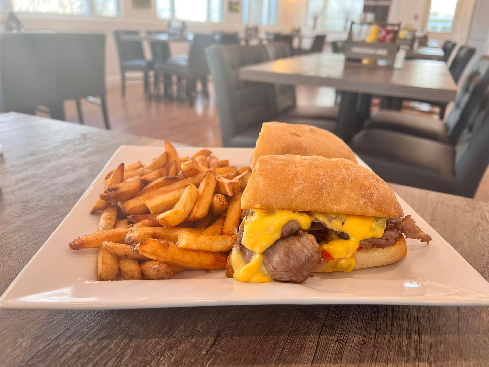A sandwich and french fries on a white plate on a table.