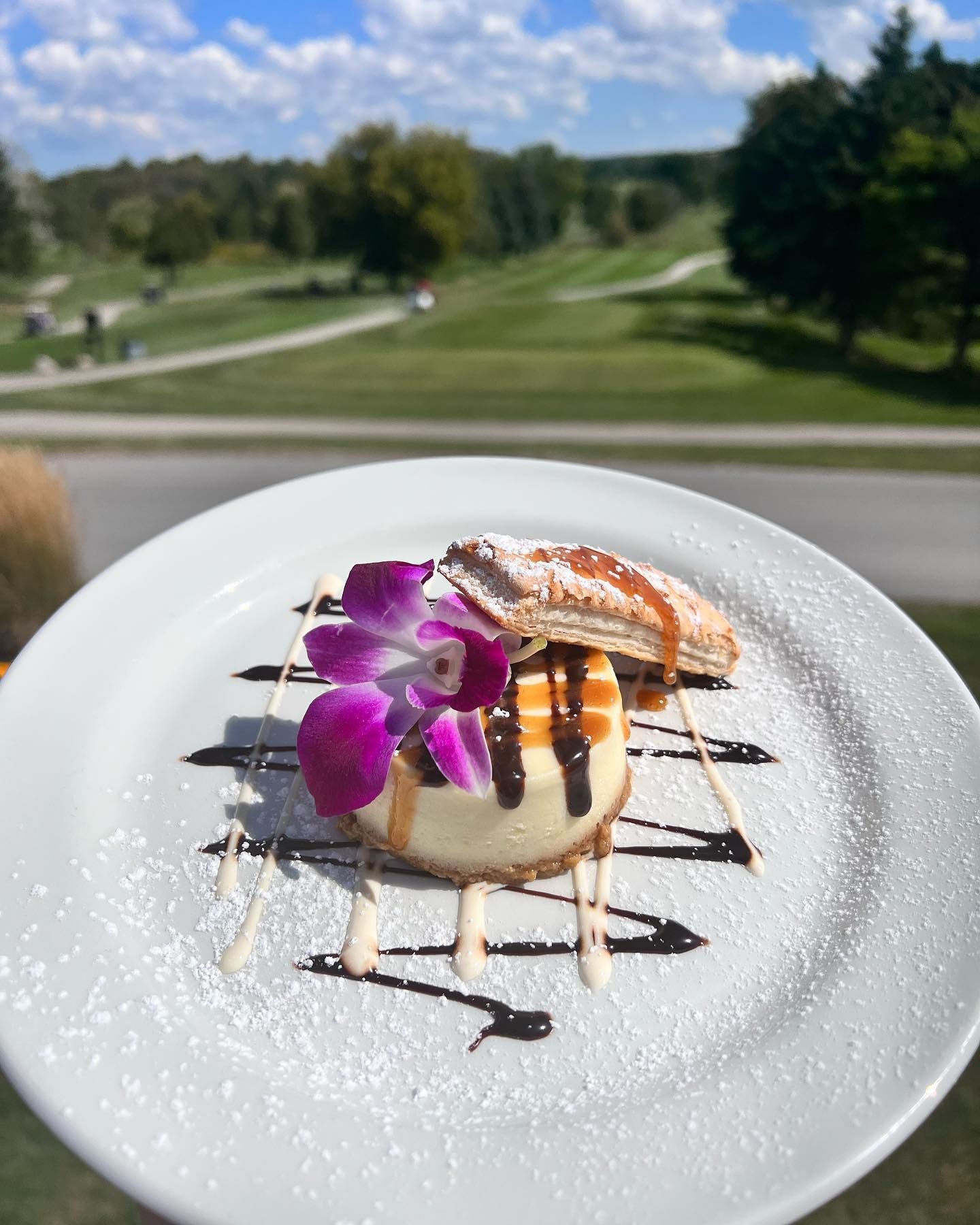 A white plate topped with a dessert and a purple flower.