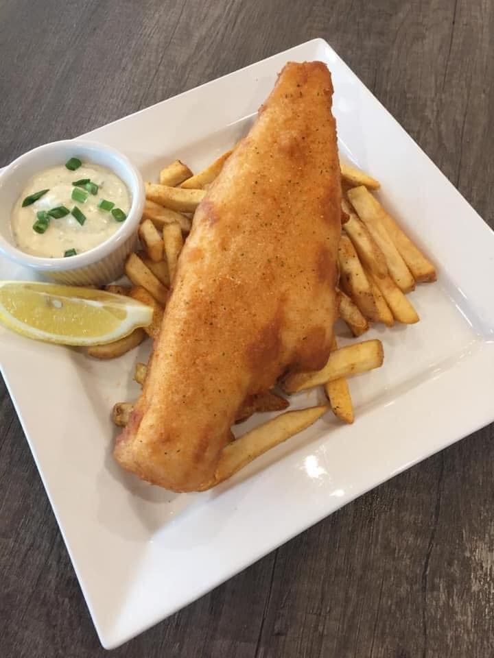 A white plate topped with fish and french fries on a table.