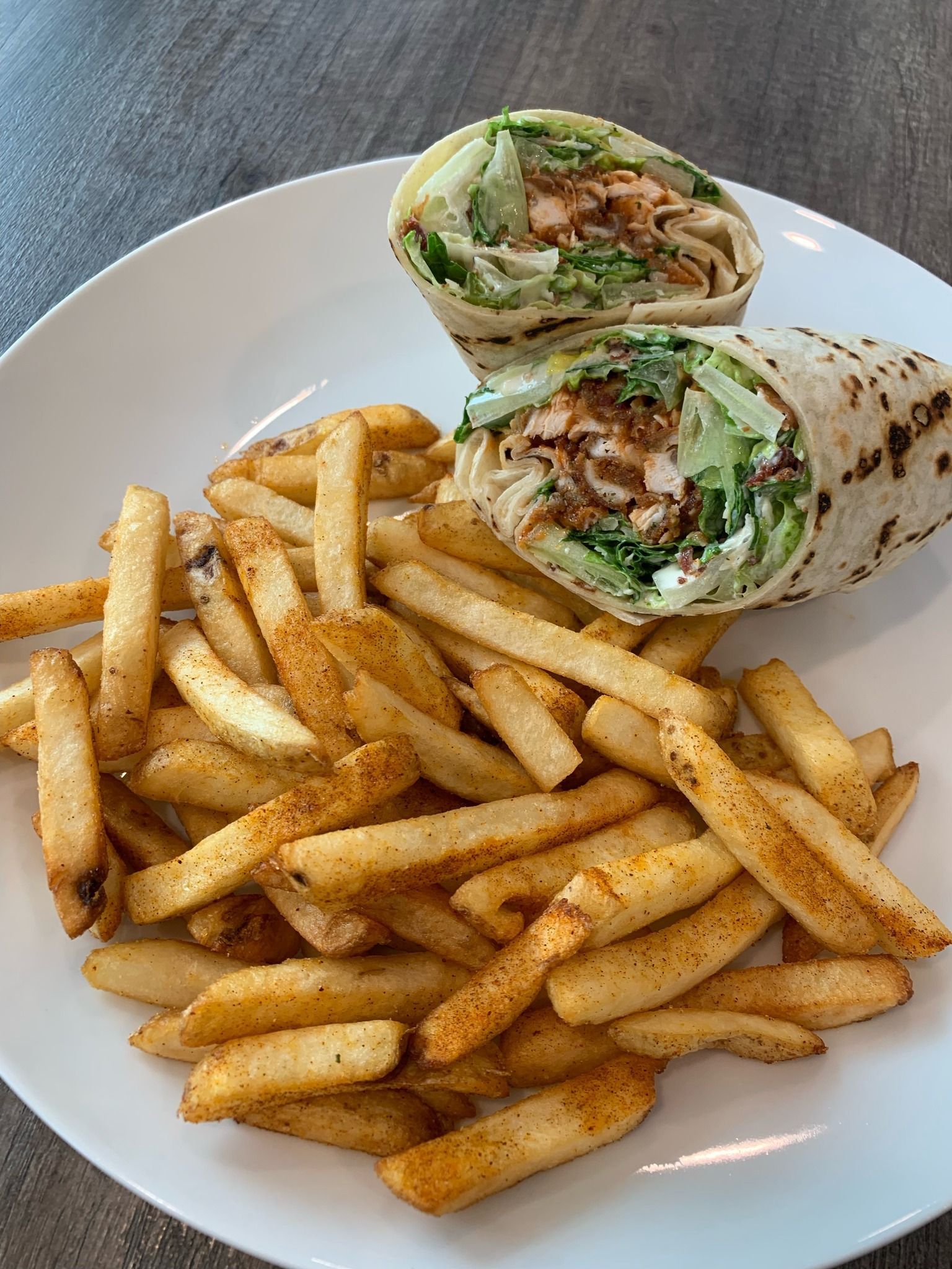 A white plate topped with a wrap and french fries.