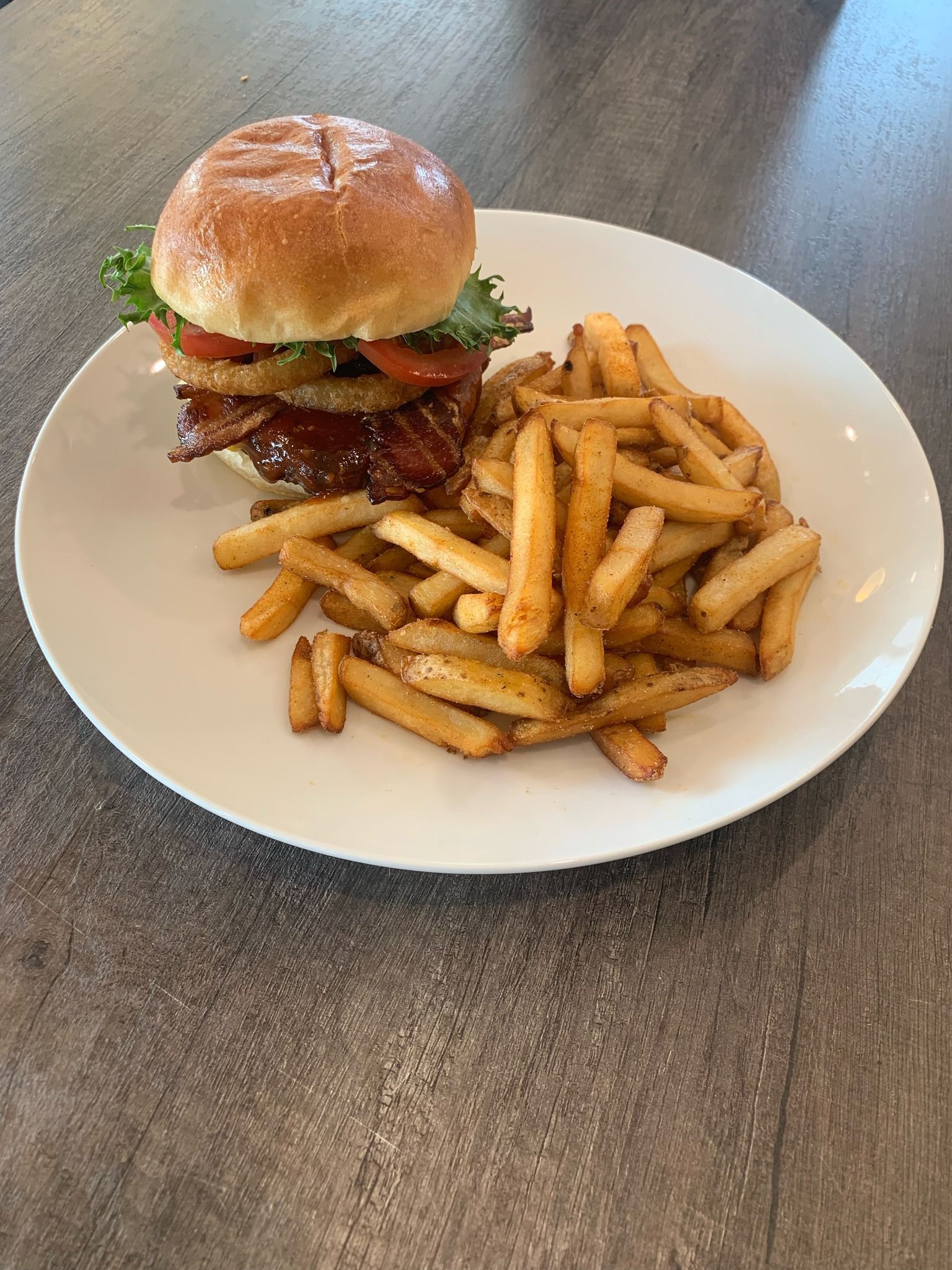 A hamburger and french fries on a white plate on a table.