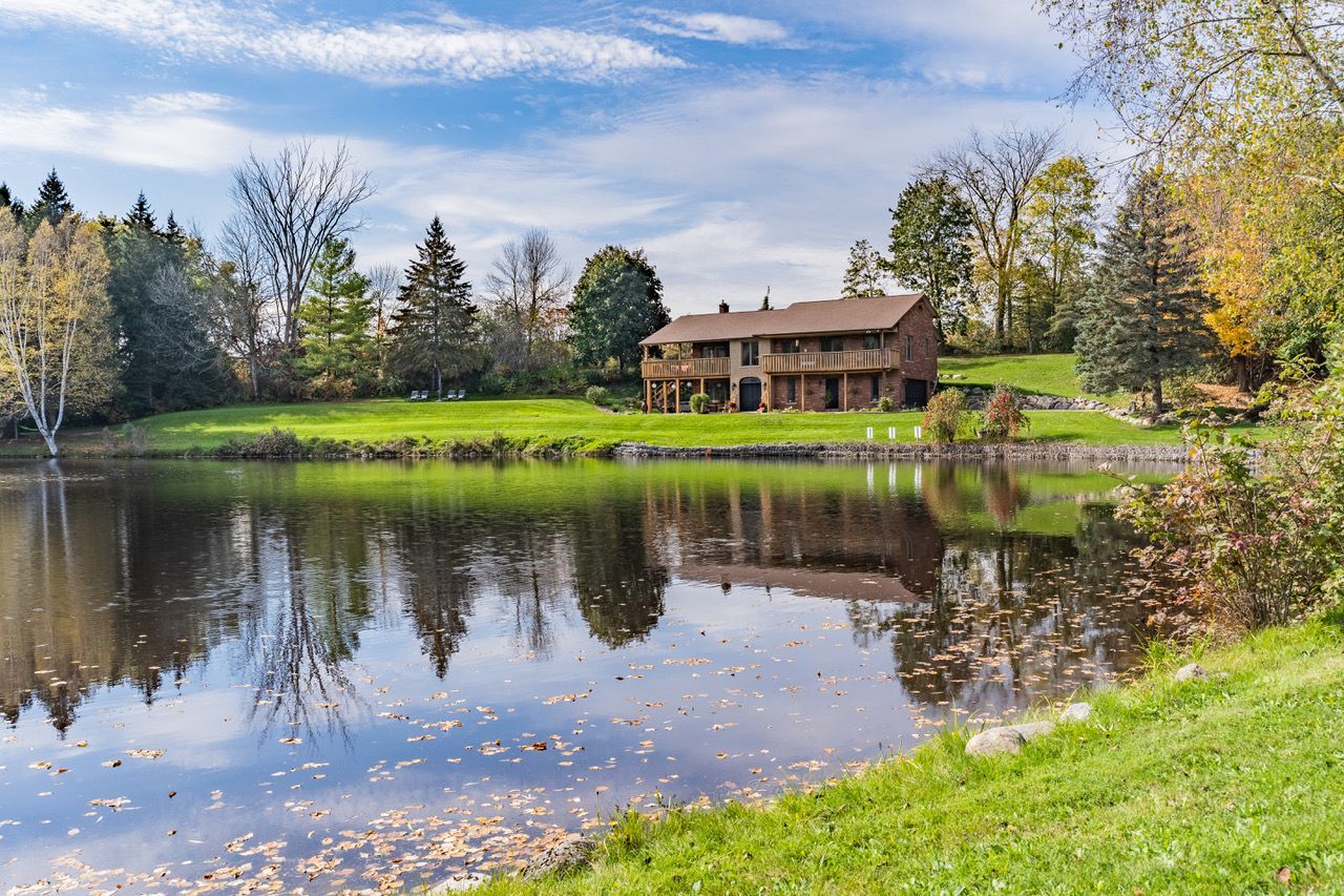 A house is sitting on the shore of a lake surrounded by trees.