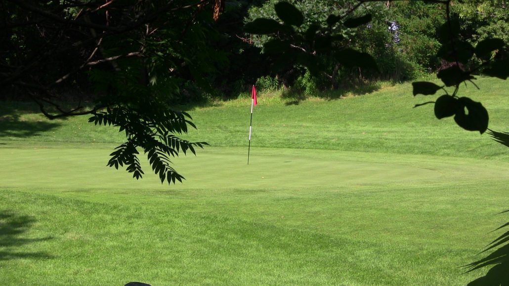 A golf course with a red flag on the green.