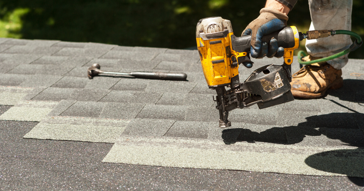 Roofer using a nail gun to install shingles during a roof replacement covered by insurance in Texas.
