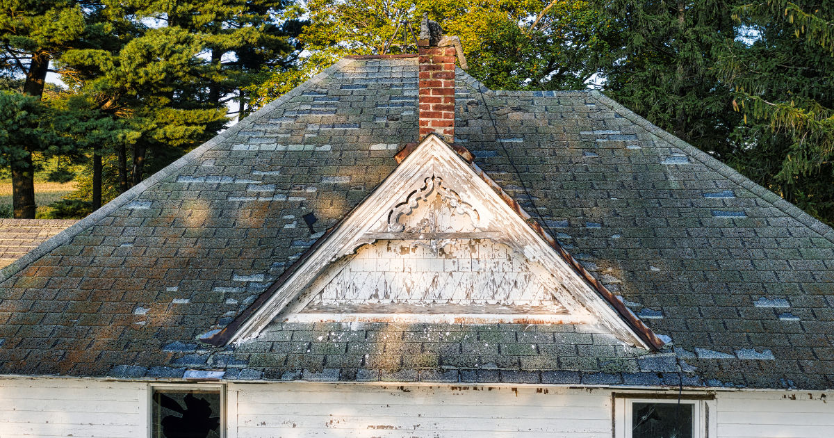 Shingle roof marked with chalk around wind damage and missing shingles during a roof insurance claim