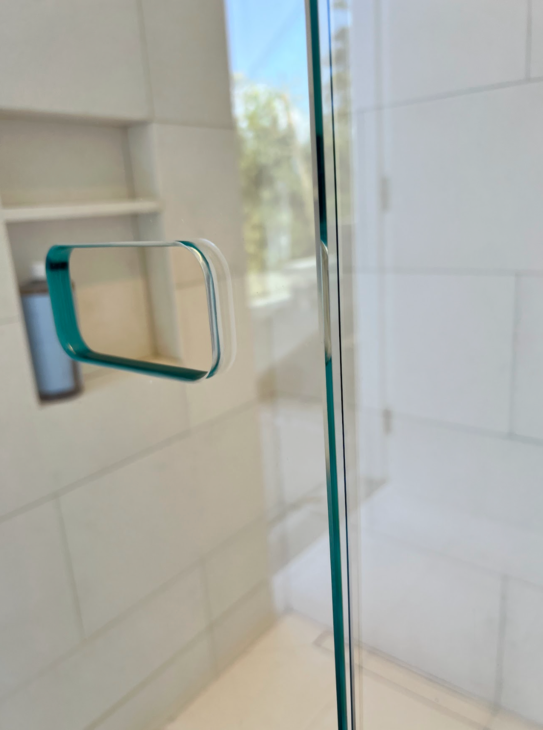 Corner shower with glass doors, white tiled walls, and a recessed soap niche.