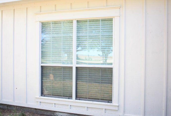White framed window with horizontal blinds on white siding.