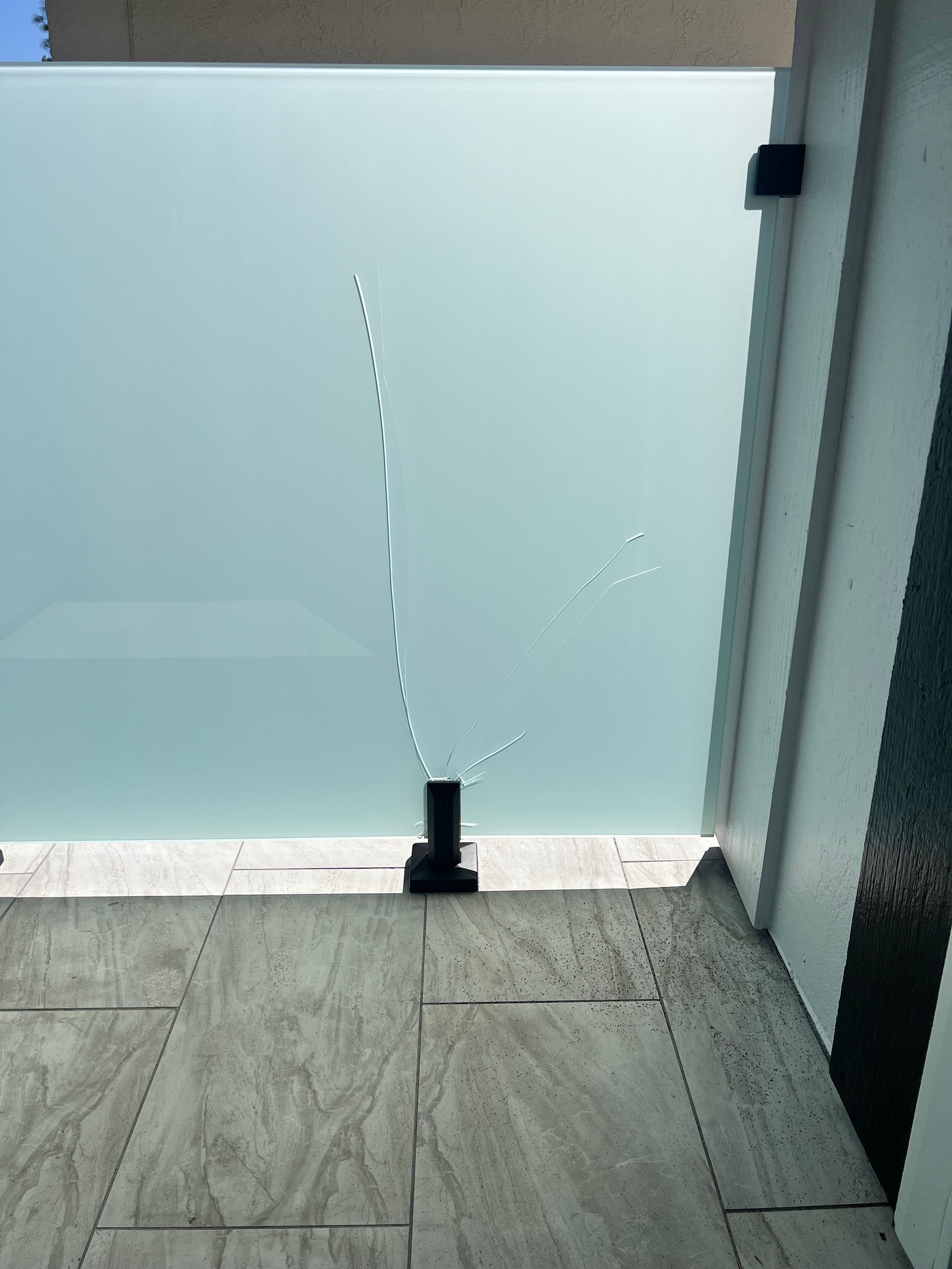 Frosted glass railing on a patio, with a line of what appears to be bird droppings on the glass.