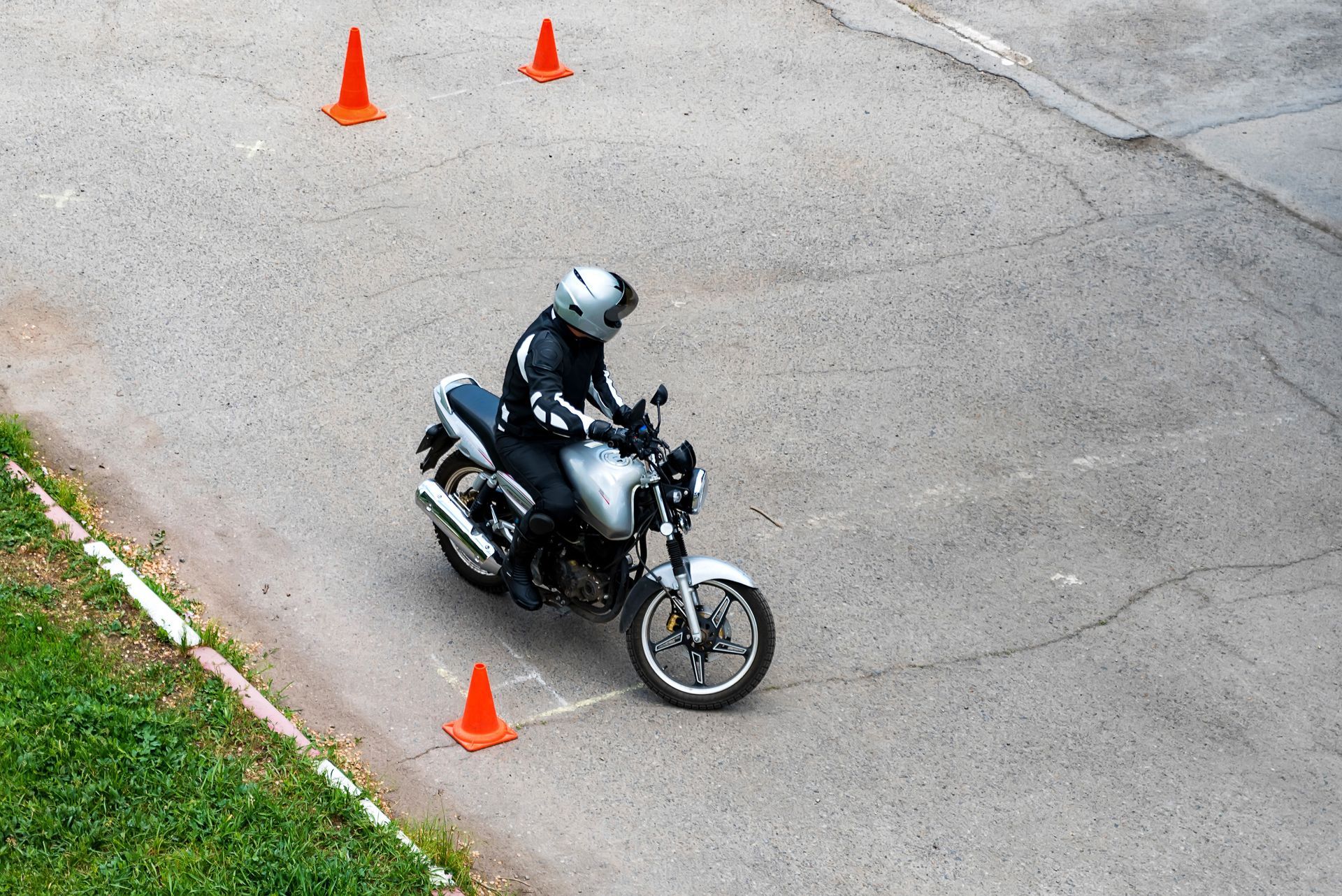 Une personne conduit une moto sur une route entourée de cônes de signalisation.