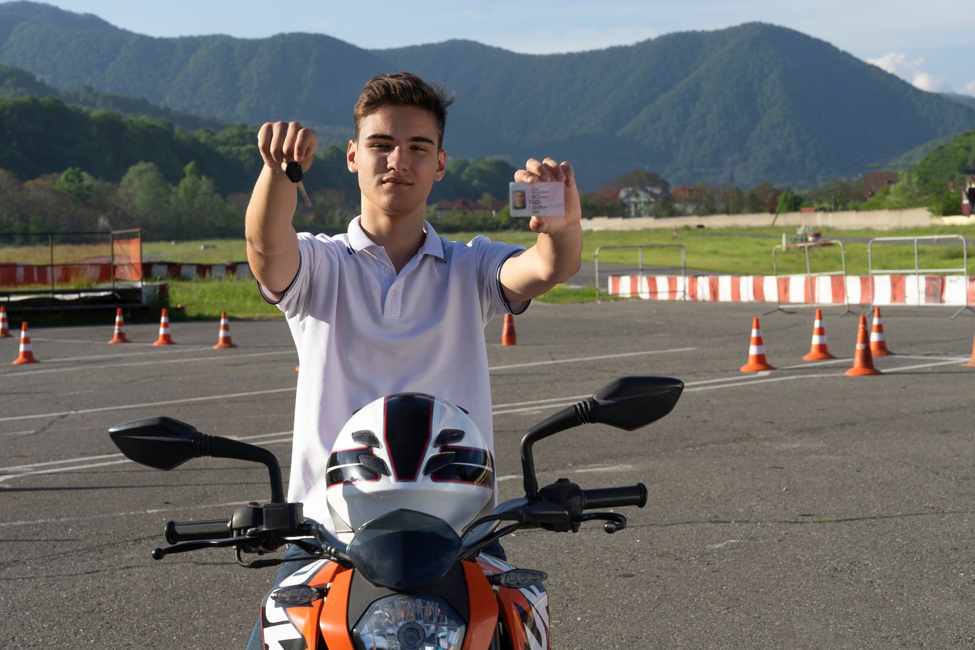 Un jeune homme est debout sur une moto et détient un permis de conduire.