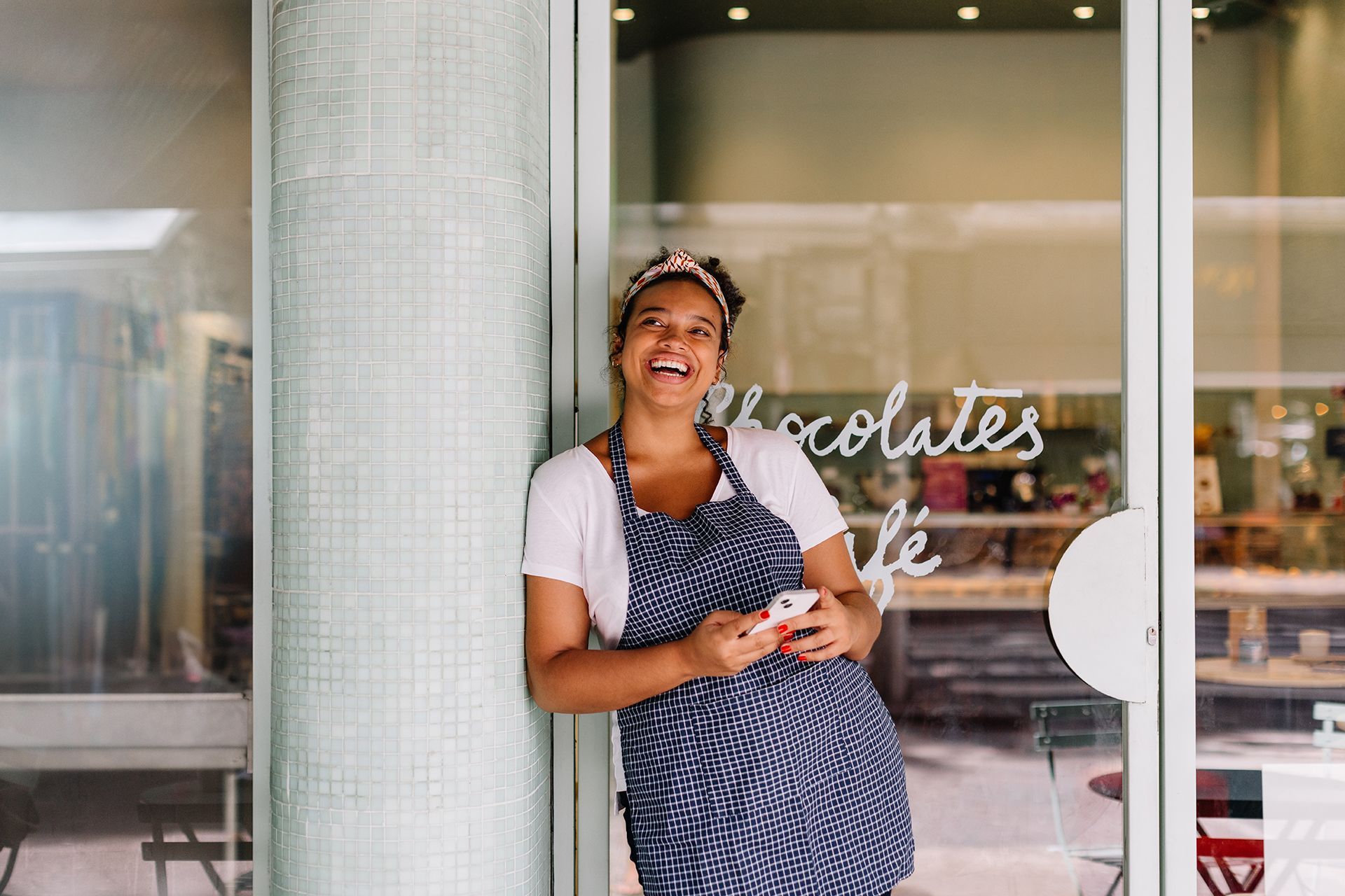 A woman is standing in front of a glass door holding a cell phone.