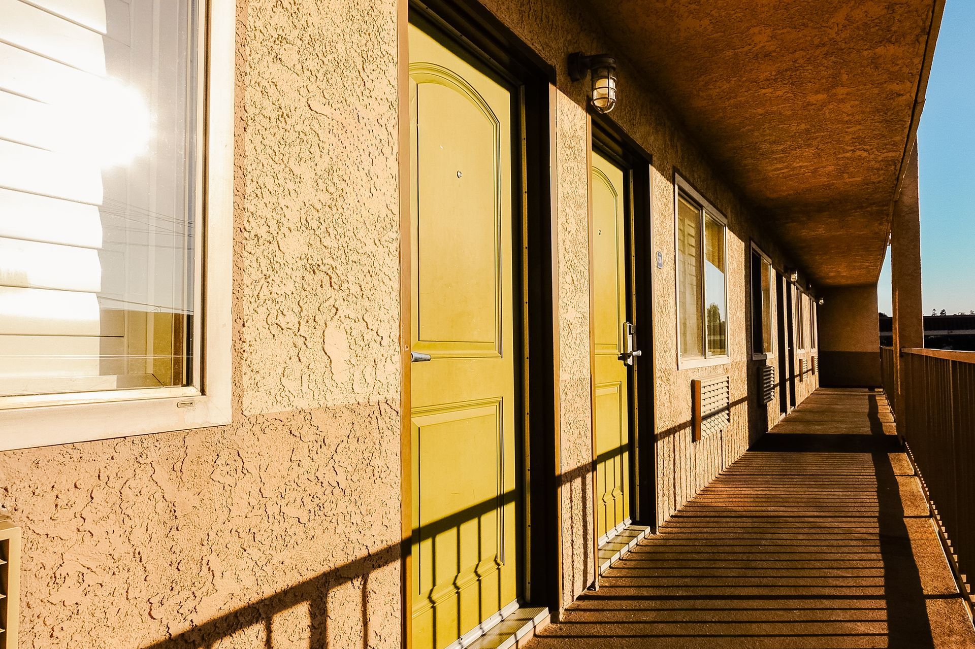 Motel exterior: beige stucco walls with yellow doors and a covered walkway.
