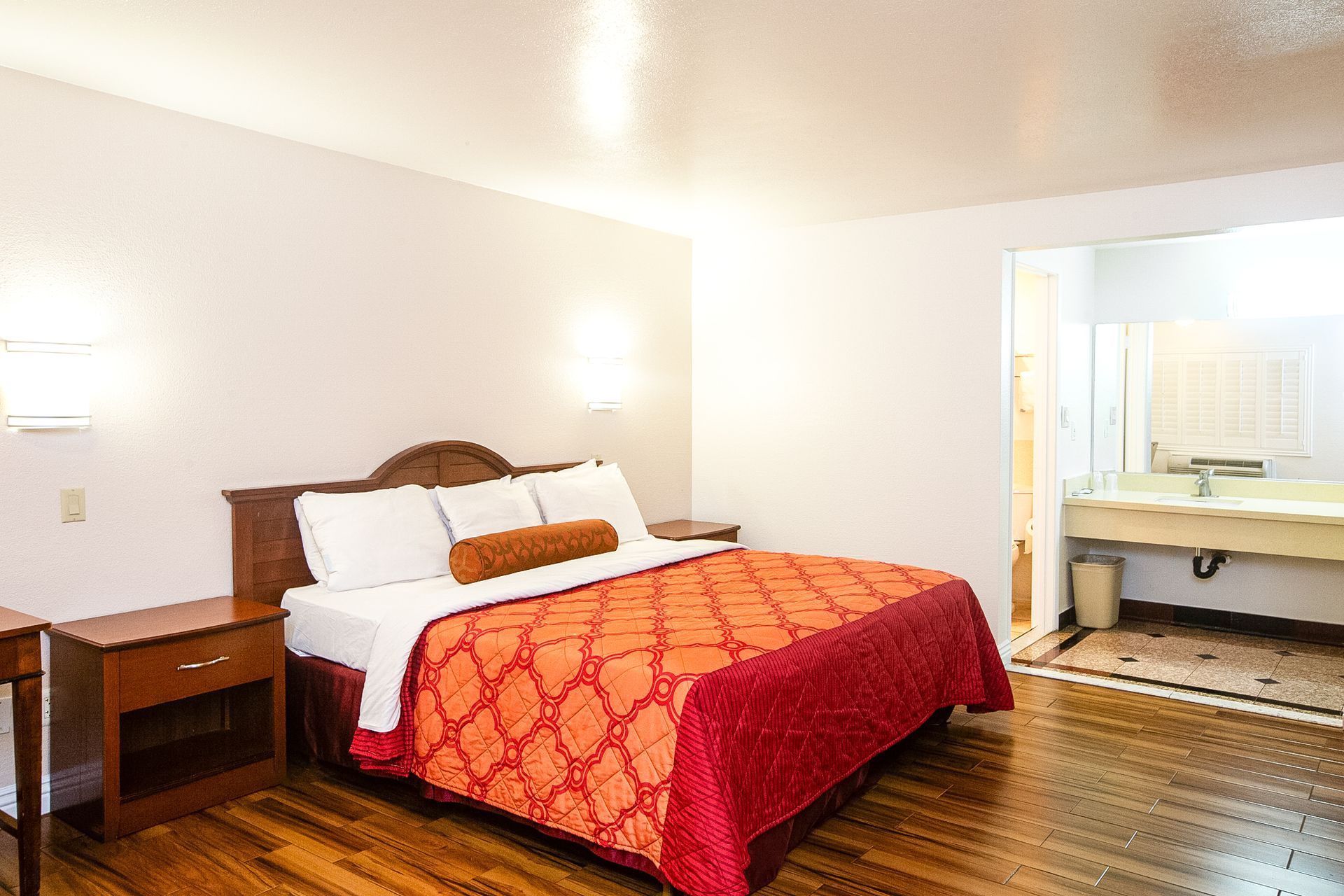 Hotel room with a queen bed, wooden floor, and bathroom visible in the background.