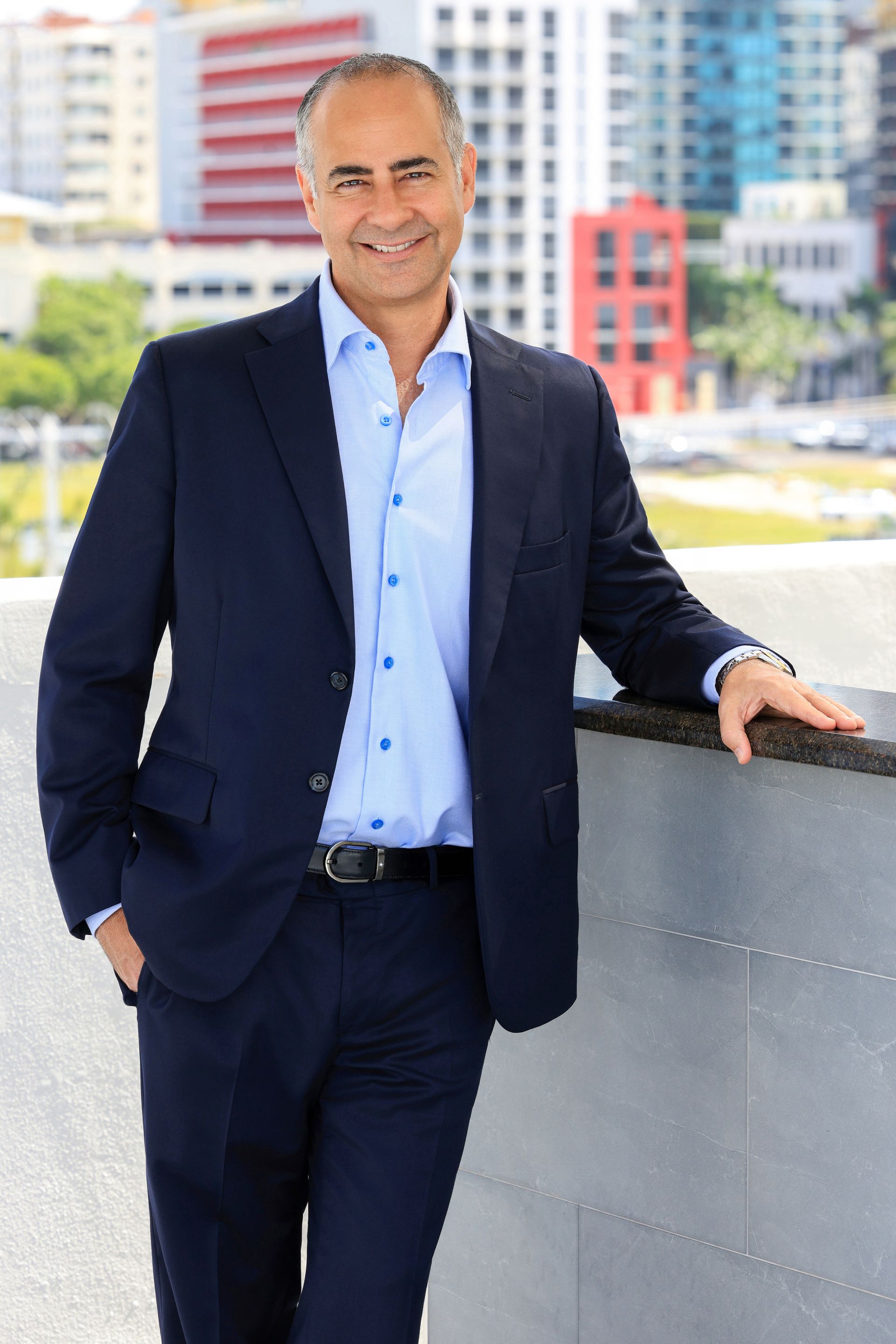 A man in a suit and plaid shirt is smiling for the camera.
