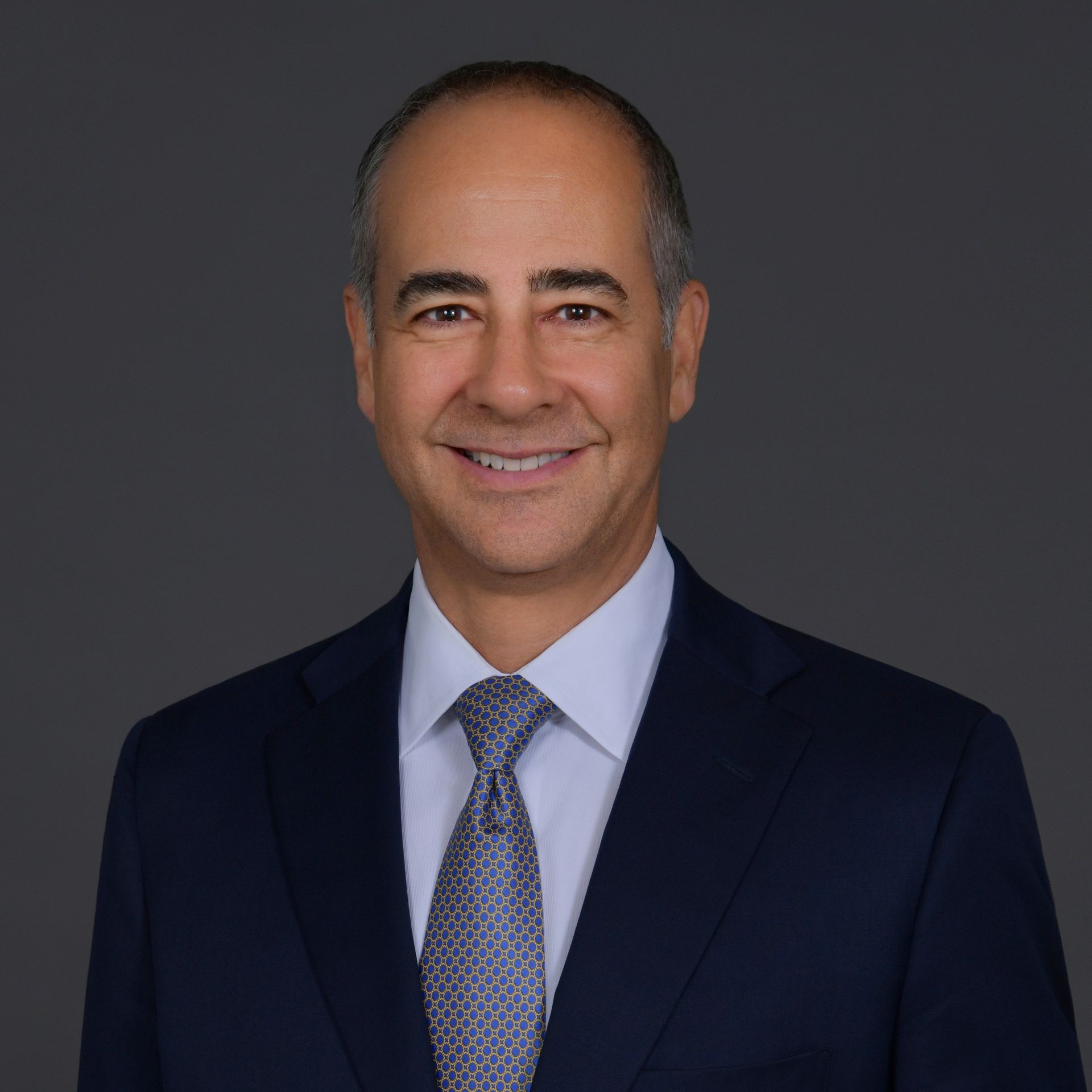 A man in a suit and tie is standing with his arms crossed.