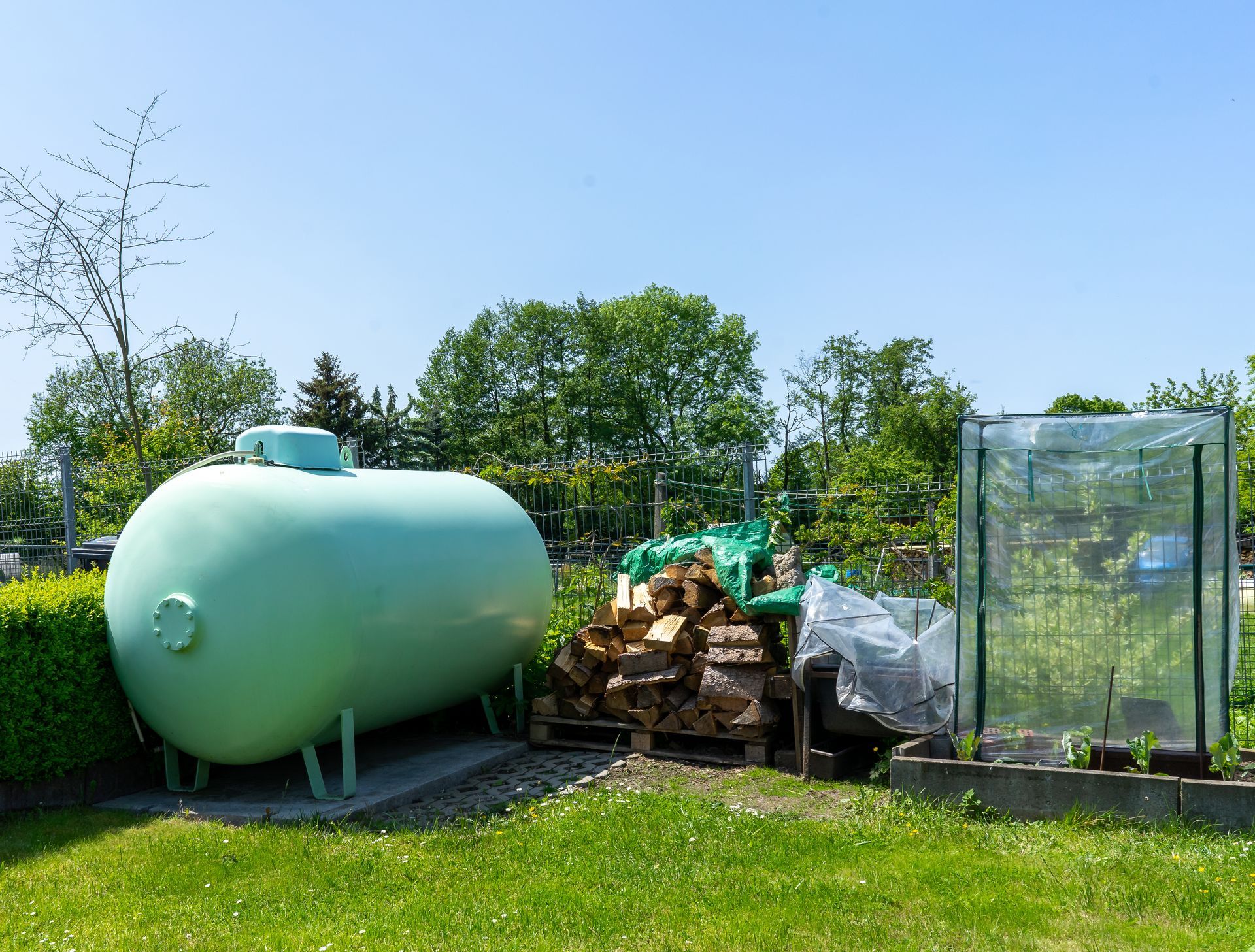 A green propane tank in a residential backyard. A green propane tank in a residential backyard.