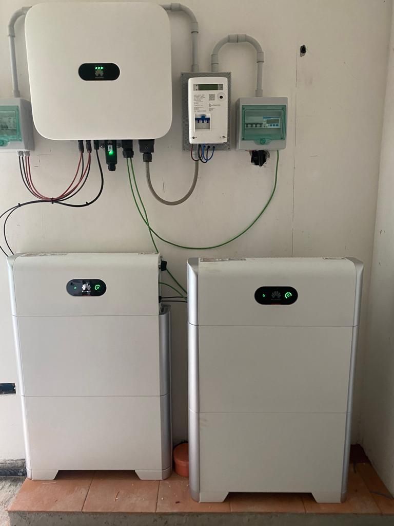 Inverter solare bianco, batterie e componenti elettrici montati su una parete.