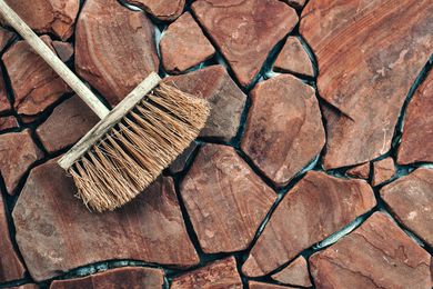 A broom is sitting on top of a rocky surface. A broom is sitting on top of a rocky surface.