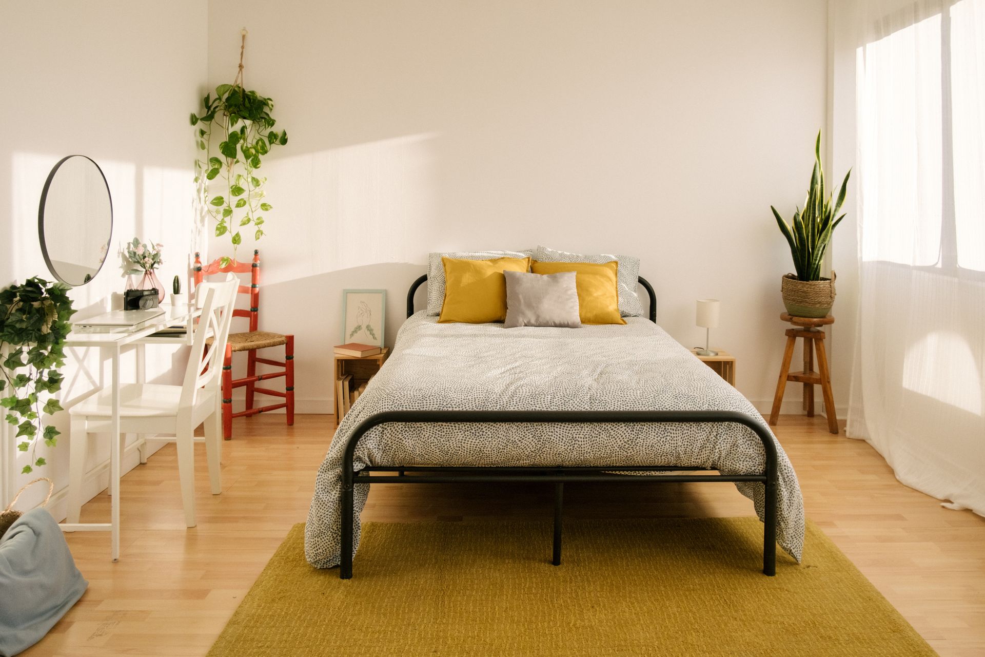 A bedroom with a bed , desk , chairs and a rug.