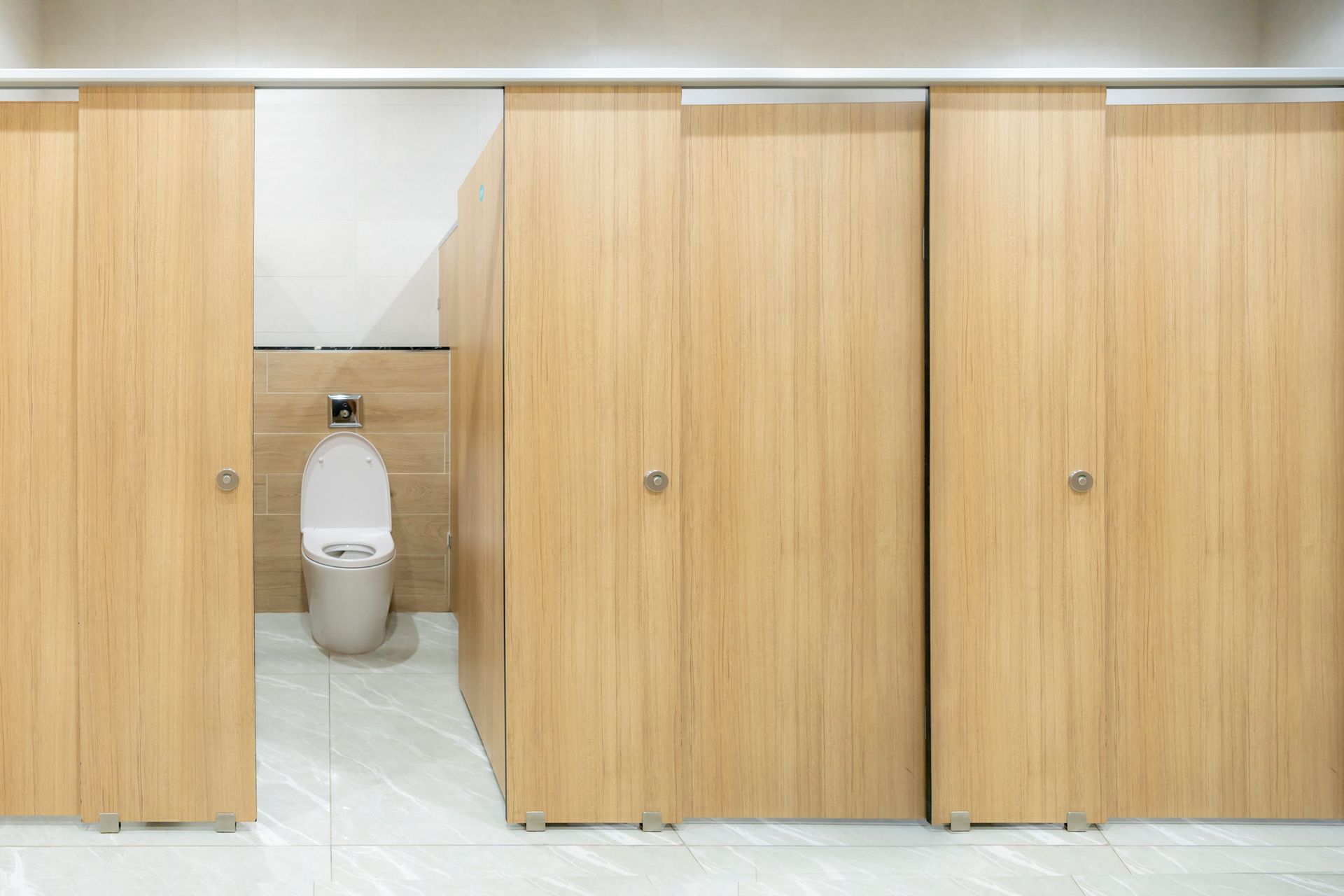 A toilet in a public restroom with wooden partitions. A toilet in a public restroom with wooden partitions.