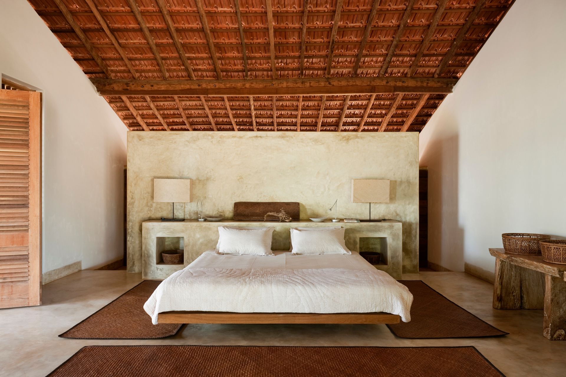 A bedroom with a large bed and a wooden ceiling A bedroom with a large bed and a wooden ceiling