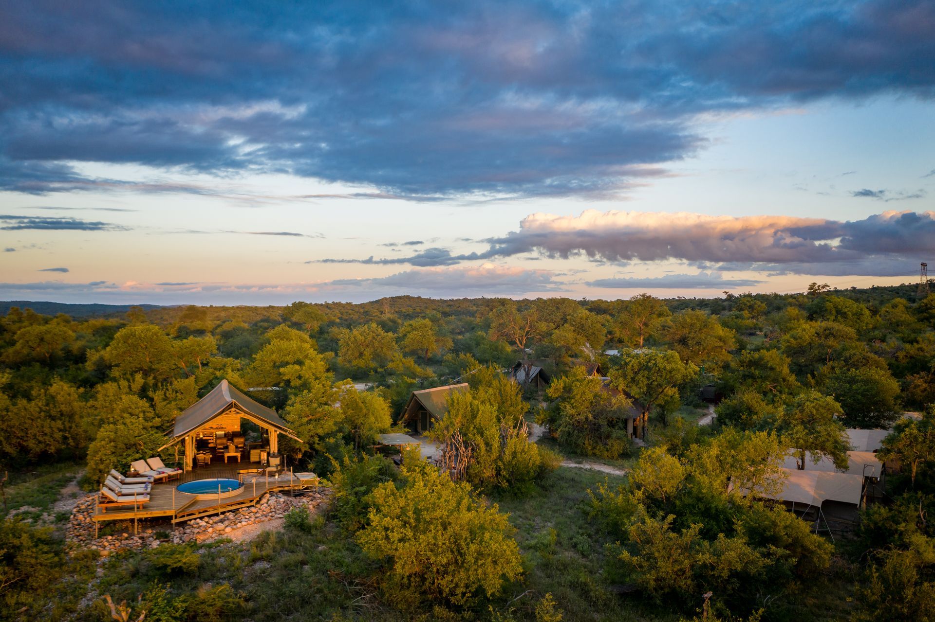 Aerial view of a wooded resort with cabins at sunset under a blue-orange sky