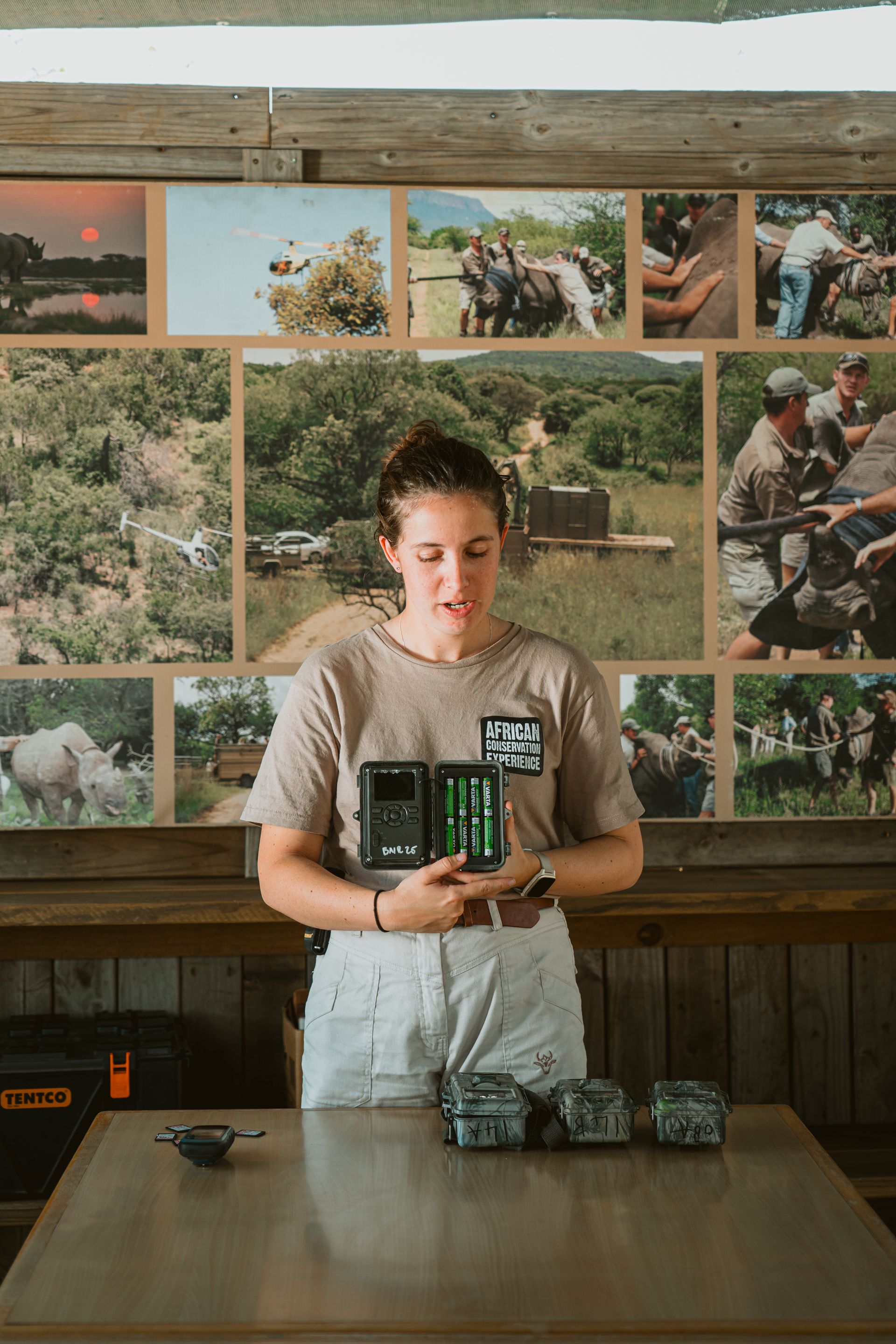 Woman holding devices, demonstrating how they work in front of a photo gallery.