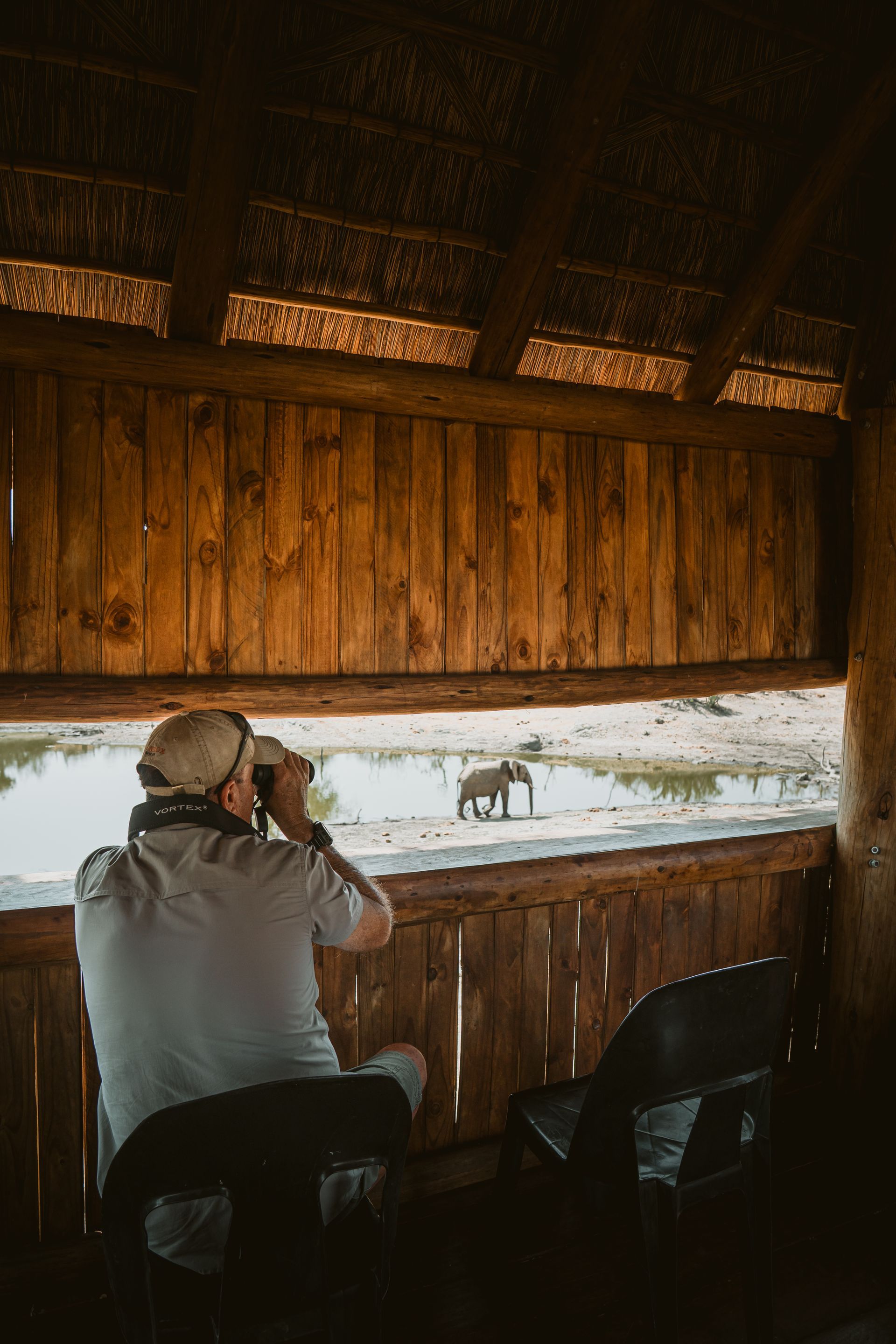Person photographing wildlife from a wooden hide overlooking a snowy landscape