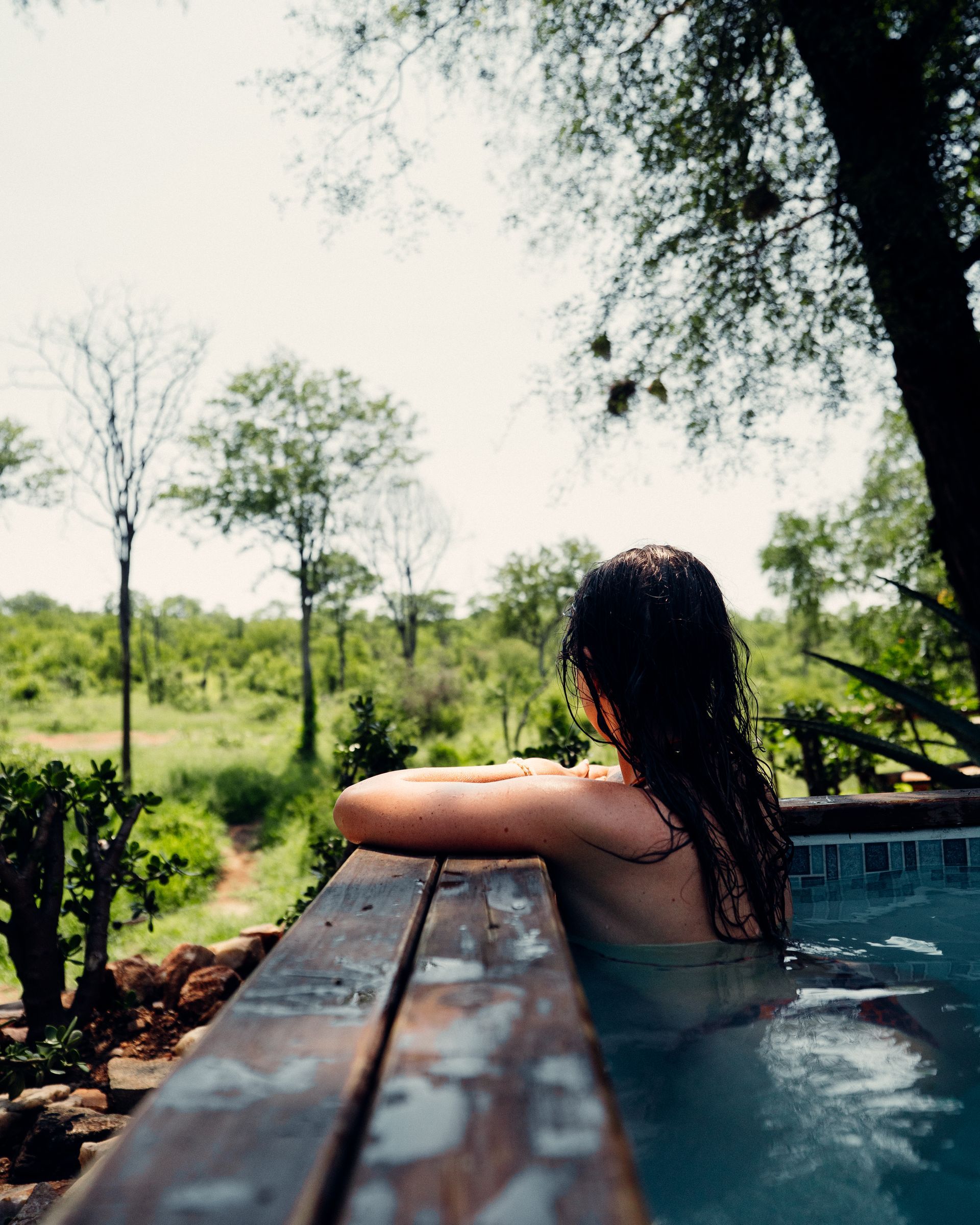 Person relaxing in a hot tub overlooking a lush green landscape