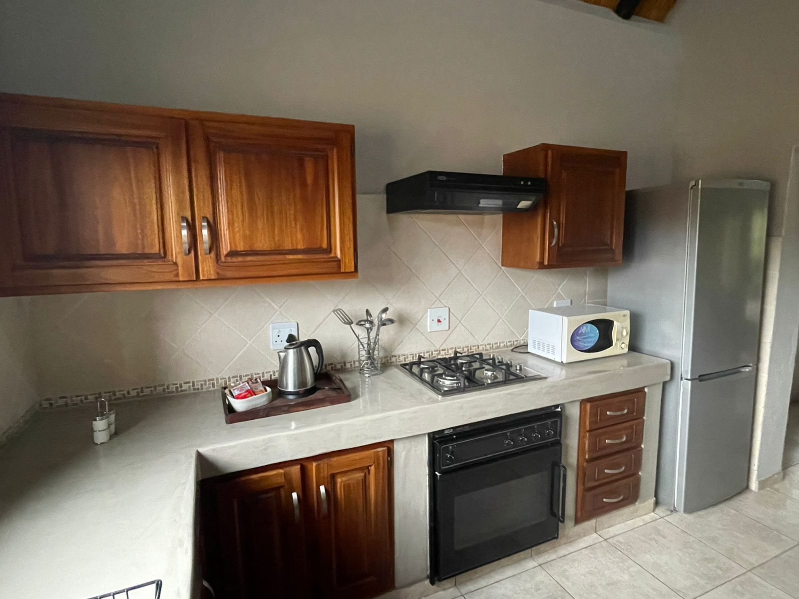 Kitchen with wooden cabinets, stove, oven, microwave, and refrigerator.