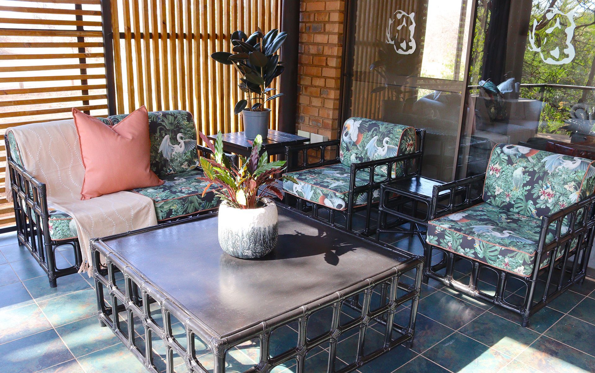 Outdoor patio with patterned furniture, coffee table, and potted plants.