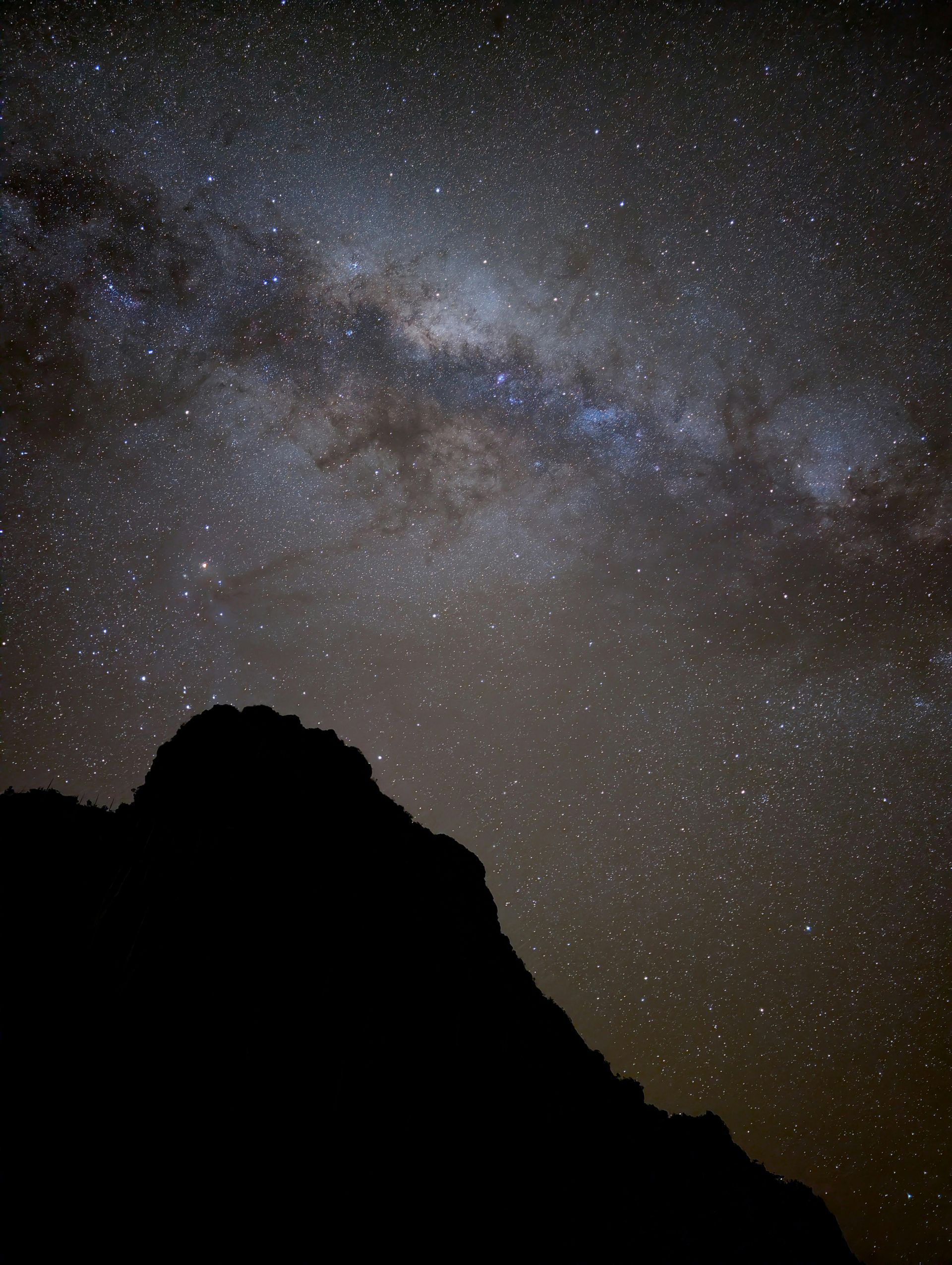 Starry night sky with the Milky Way above a dark mountain silhouette
