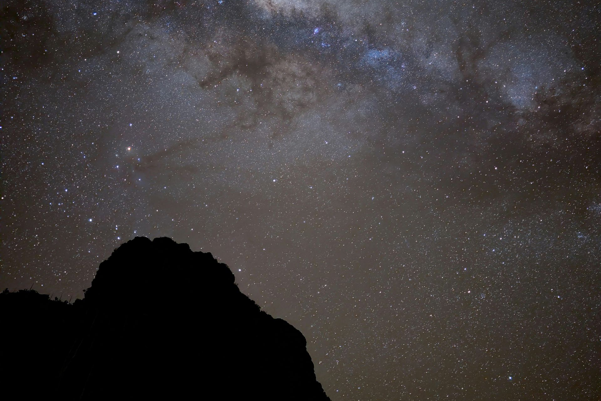 Starry night sky above a dark mountain silhouette