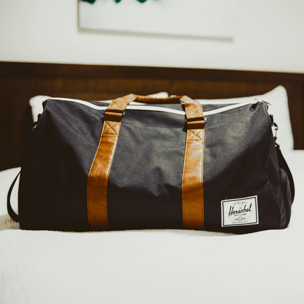 Gray duffel bag with brown straps on a white surface