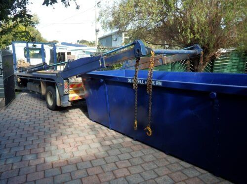 A Blue Dumpster Is Sitting on A Brick Driveway Next to A Truck — H & H Metal Recycling In Warana, QLD