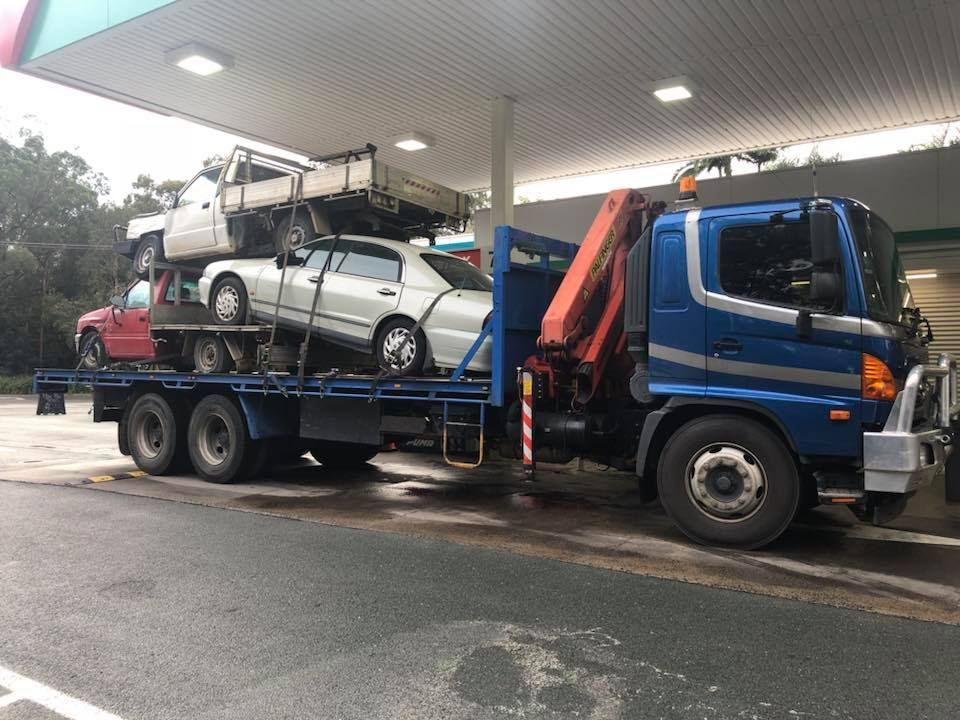 Blue Truck Carrying Multiple Cars At A Gas Station — H&H Metal Recycling in Mudjimba, QLD