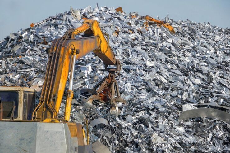 A Yellow Excavator Is Working on A Pile of Scrap Metal — H & H Metal Recycling In Caboolture, QLD