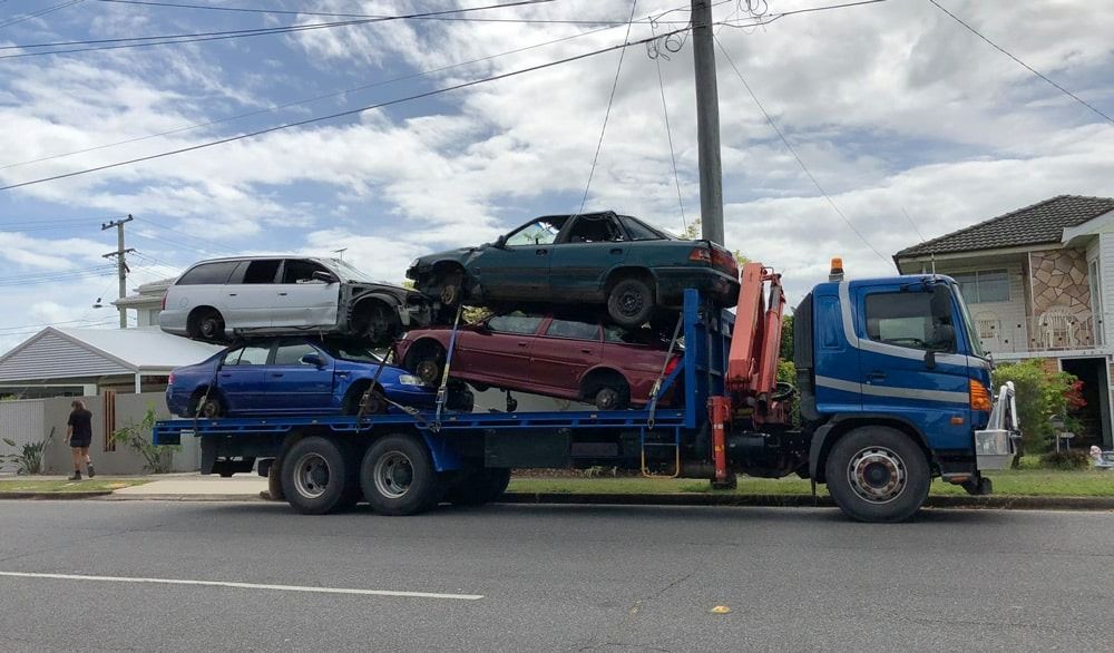 A Blue Tow Truck Is Carrying a Bunch of Cars on The Back of It — H & H Metal Recycling In Warana, QLD