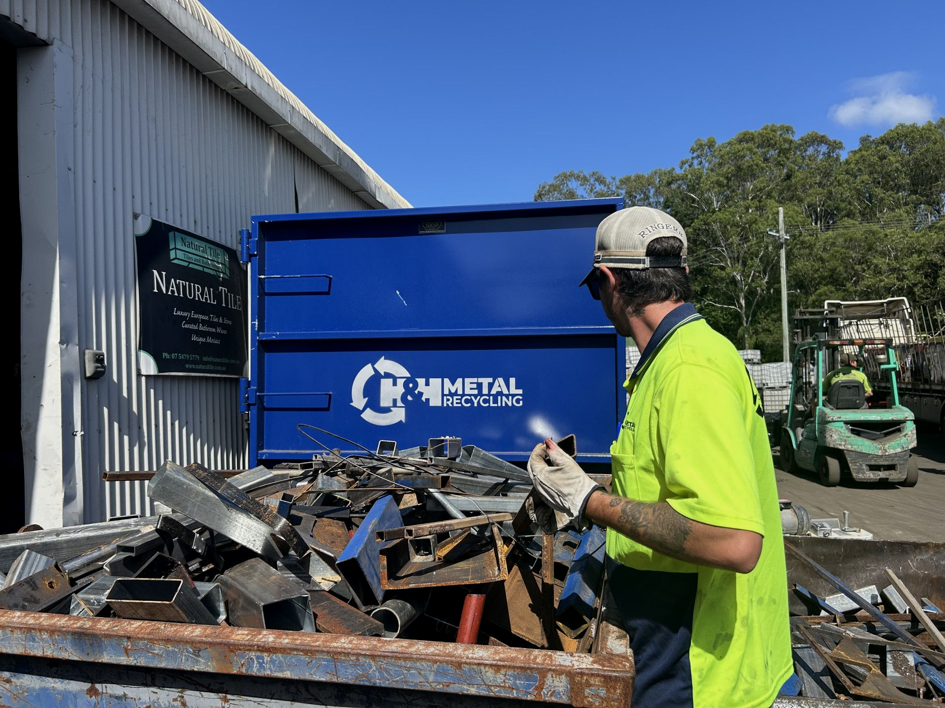 A Green Truck with A Crane Attached to It Is Being Towed by A Blue Truck — H & H Metal Recycling In Coolum, QLD