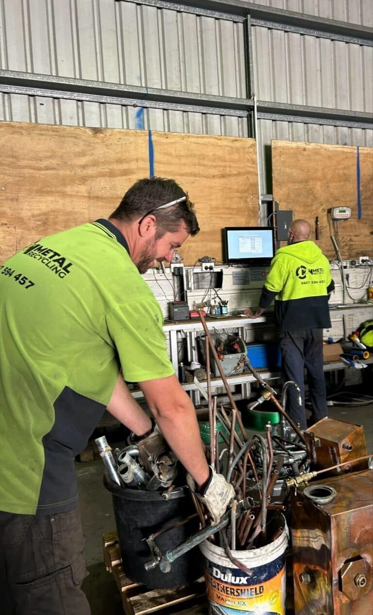 A Man in A Green Shirt Is Working in A Warehouse — H & H Metal Recycling In Kunda Park, QLD