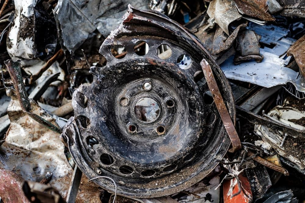 A Close up Of a Rusty Wheel in A Pile of Scrap Metal — H & H Metal Recycling In Warana, QLD
