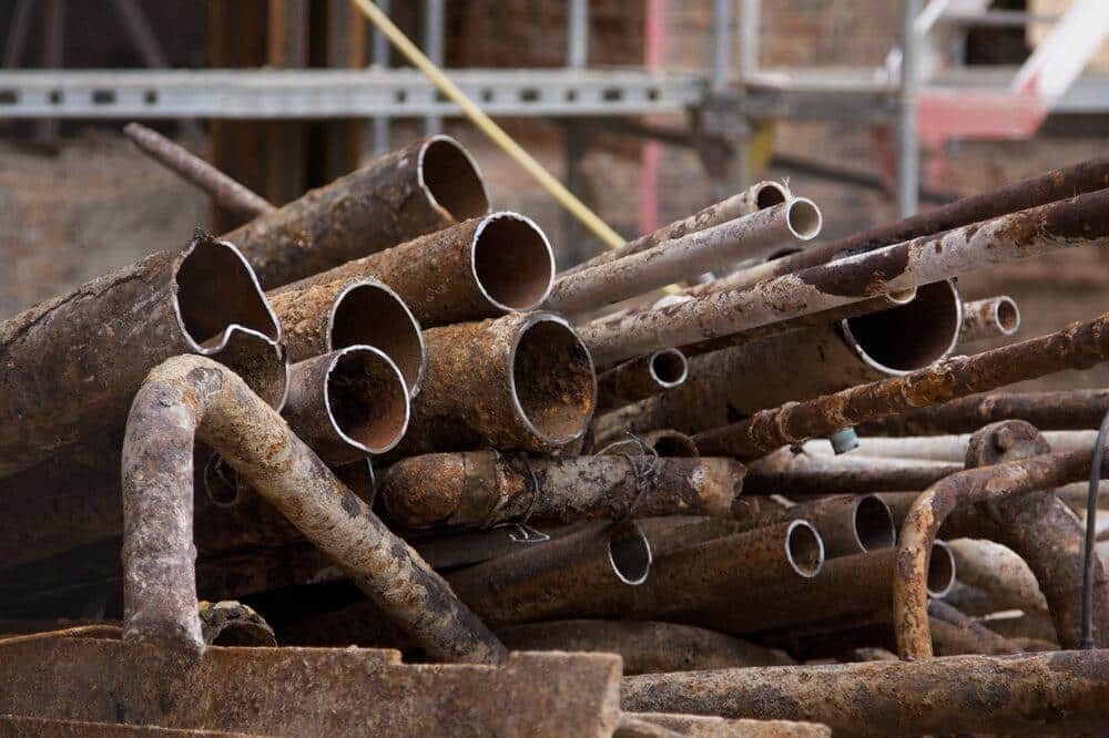 A Pile of Rusty Metal Pipes Sitting on Top of Each Other — H & H Metal Recycling In Landsborough, QLD