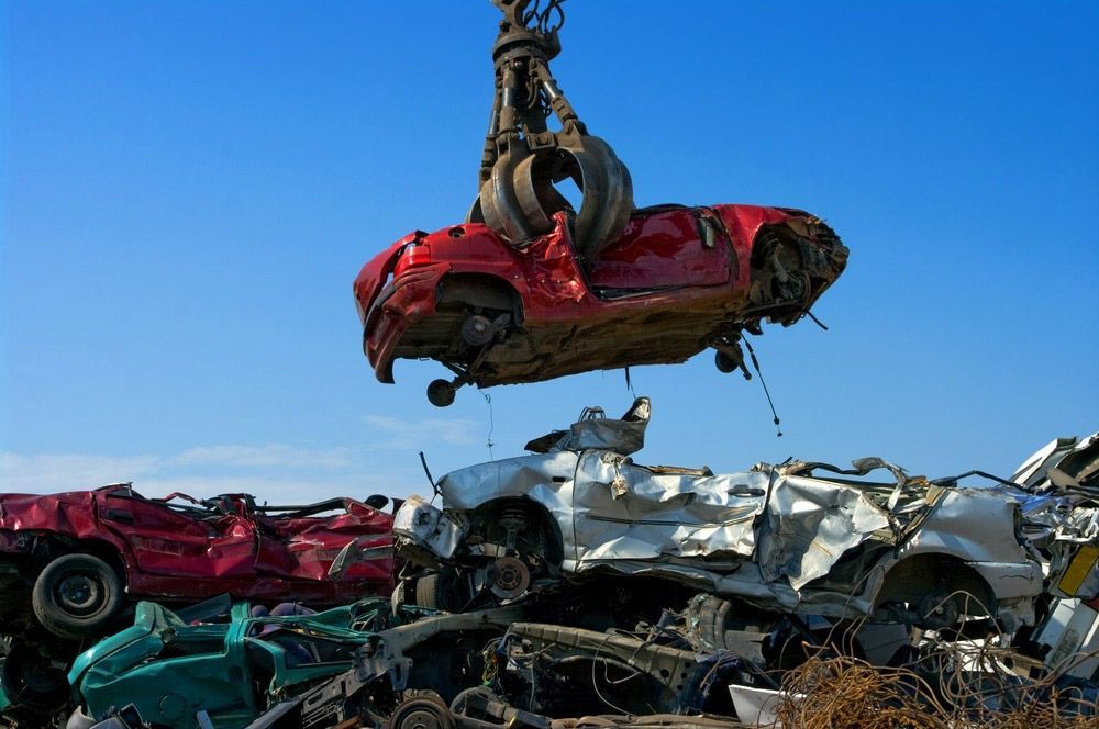 A Red Car Is Being Lifted Into the Air by A Crane — H & H Metal Recycling In Warana, QLD