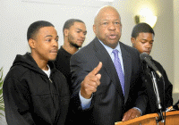 A child and a uniformed police officer stand in front of a police station with glass doors.