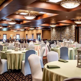 Elegant banquet hall with round tables, white chair covers, and warm ceiling lights
