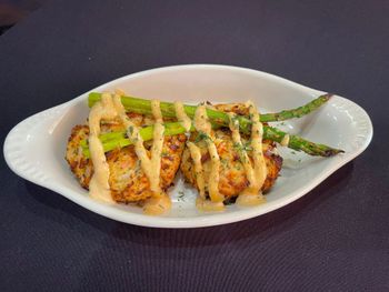 Grilled chicken skewers on a white plate with asparagus and a drizzle of sauce